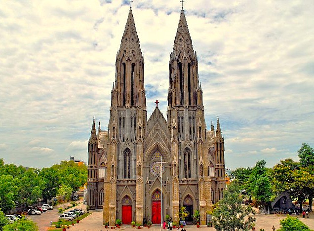 Experience Gothic grandeur at Saint Philomenas Cathedral in Mysore, Karnataka, India, en route from Bangalore to Coimbatore, with the shimmering Mysore Palace lit up nearby—a majestic heritage and architectural masterpiece.