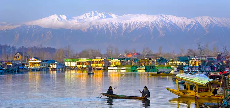 Men row a boat on Dal Lake in Srinagar, Jammu and Kashmir, past houseboats with snow-capped mountains, a region famous for its nearby saffron fields. Men row a boat on Dal Lake in Srinagar, Jammu and Kashmir, past houseboats with snow-capped mountains, a region famous for its nearby saffron fields.