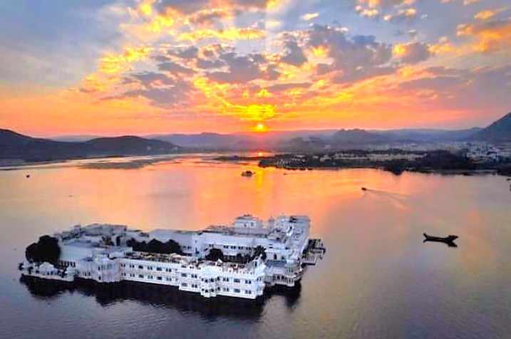 "Admire the sunset over the Taj Lake Palace in Rajasthan, India, a romantic highlight complementing your journey to Delhi, Varanassi, and to visit Unesco Taj mahal."