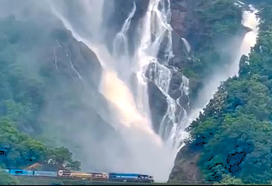 A train passing the magnificent Dudhsagar Falls in Goa, India, a breathtaking stop on a scenic Karnataka road trip connecting Hubli to Hampi's Unesco sites.