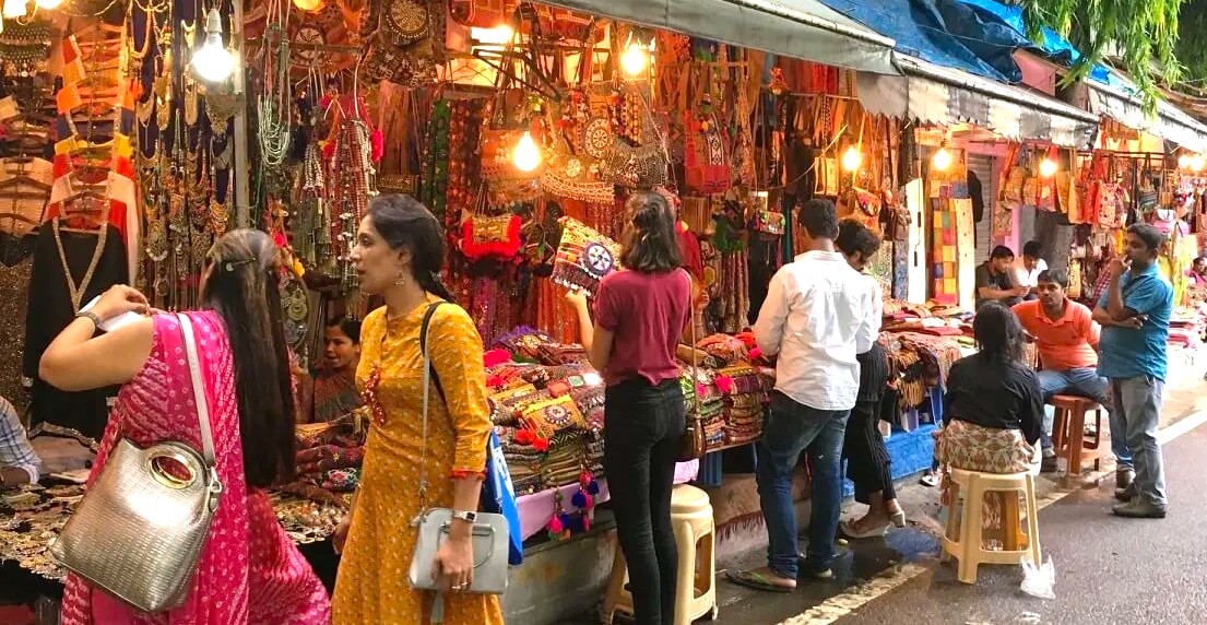 “A vibrant crowd of shoppers explores colorful textile and jewelry stalls, admiring handcrafted accessories and ethnic patterns under hanging lanterns at Delhi’s famous Tibetan Market in India’s bustling artisan bazaar.”  “A vibrant crowd of shoppers explores colorful textile and jewelry stalls, admiring handcrafted accessories and ethnic patterns under hanging lanterns at Delhi’s famous Tibetan Market in India’s bustling artisan bazaar.”