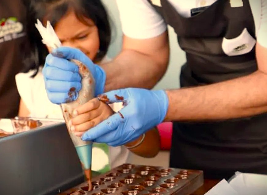 A child learns chocolate making at Moddys in Ooty, South India, near the Dodbetta Tea Plantation, part of the scenic UNESCO Western Ghats, a sweet tradition of India.