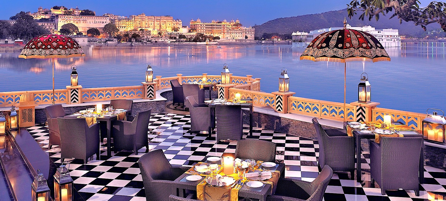 Waterfront rooftop restaurant in Udaipur, India with palace views, sunset group dining, luxury outdoor seating, candlelit tables, lakeside ambience, ideal for India tours, small groups, hosted tour dinners Waterfront rooftop restaurant in Udaipur, India with palace views, sunset group dining, luxury outdoor seating, candlelit tables, lakeside ambience, ideal for India tours, small groups, hosted tour dinners