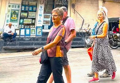 Three tourists walking through a vibrant street in Mumbai, India, near UNESCO-listed Elephanta Caves, embodying the essence of the scenic Aurangabad railway journey to the historic Elora and Ajanta Caves.