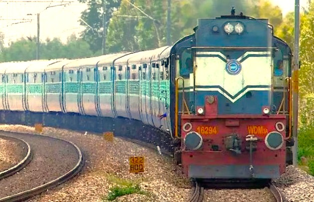 Vintage Indian train locomotive rolls along curved tracks through lush countryside near Mumbai’s UNESCO-listed Elephanta Caves, carrying travelers on the scenic Aurangabad railway journey destined for Elora and Ajanta Caves.