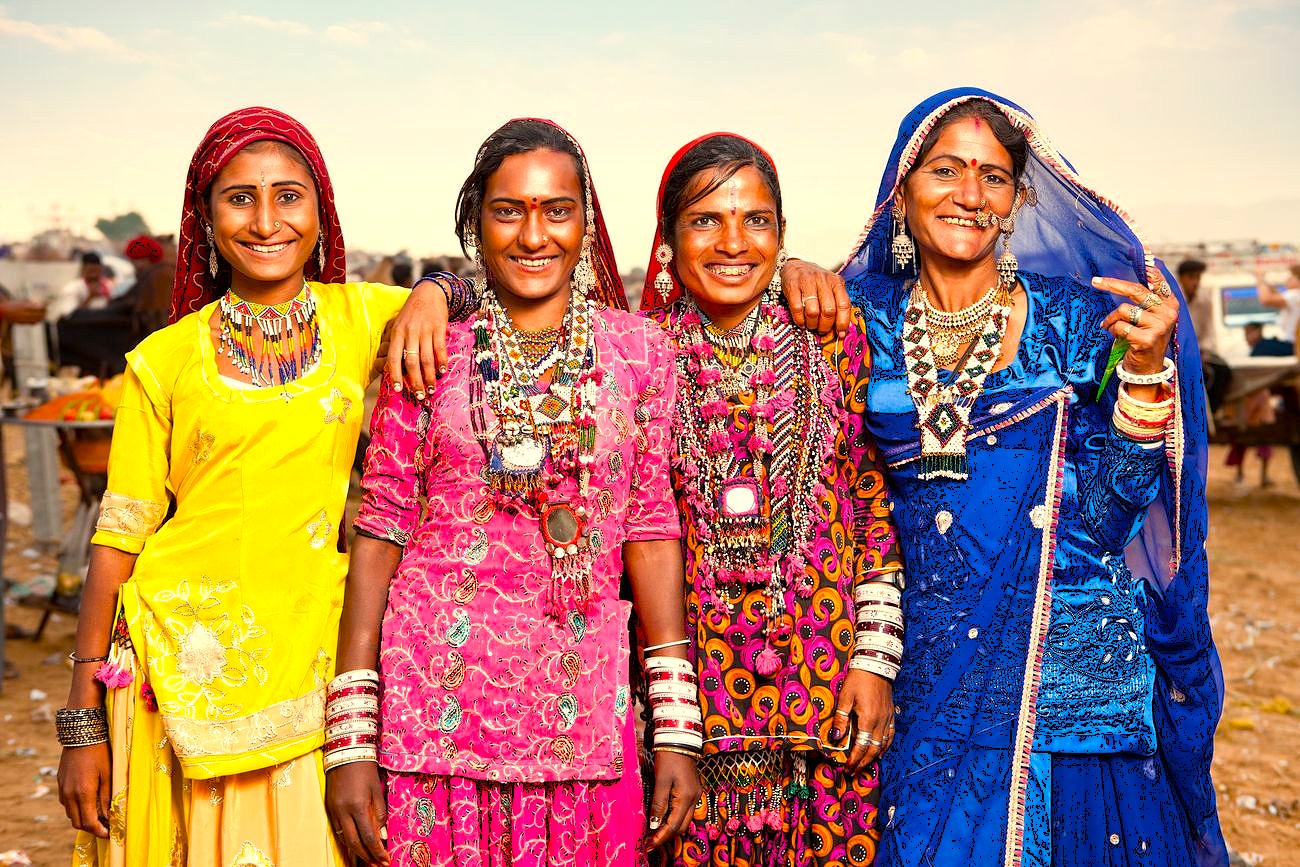 Four smiling Rajasthani women in colorful traditional dress near the historic Ahar Cenotaphs in Jaipur, India, representing the vibrant local culture for tourists visiting the UNESCO city of Udaipur