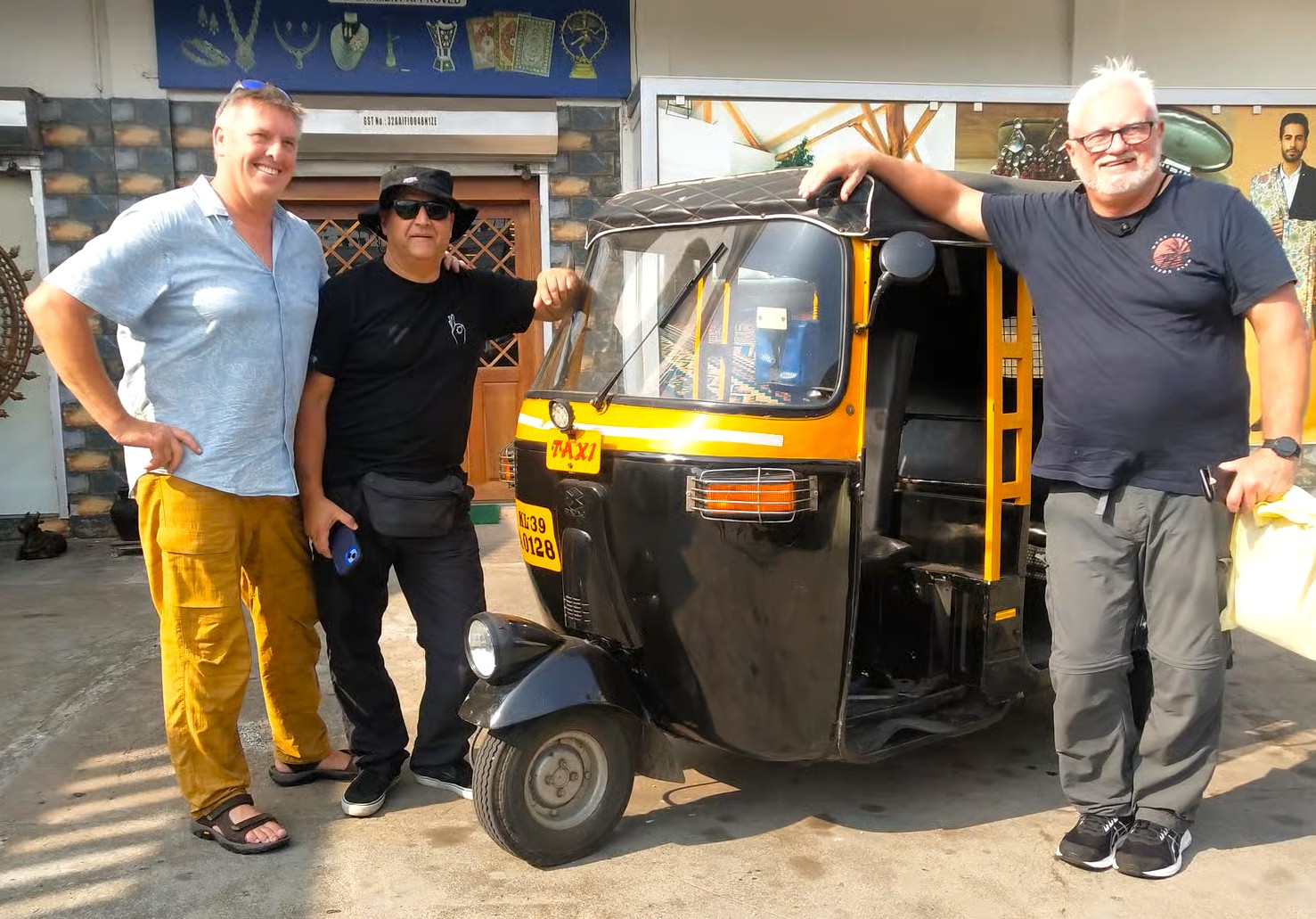 Three friendly smiling foreign tourists pose beside a black-and-yellow auto rickshaw taxi at Ambrai Ghat, Udaipur, Rajasthan, India, highlighting vibrant street culture, scenic lakefront ambiance, unique authentic local transportation experience. Three friendly smiling foreign tourists pose beside a black-and-yellow auto rickshaw taxi at Ambrai Ghat, Udaipur, Rajasthan, India, highlighting vibrant street culture, scenic lakefront ambiance, unique authentic local transportation experience.