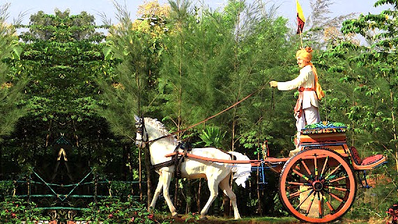 A life-size statue of a man on a traditional horse-drawn chariot at Utsav Rock Garden in Hubli, Karnataka, India, a key stop on a road trip near-Goa's Unesco Churches. A life-size statue of a man on a traditional horse-drawn chariot at Utsav Rock Garden in Hubli, Karnataka, India, a key stop on a road trip near-Goa's Unesco Churches.