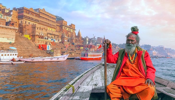 "Serene boat ride on the Ganges River in Varanasi, Uttar Pradesh, India near Sanarth Temple Buddha captures ancient ghats, spiritual pilgrimage atmosphere, historic architecture, vibrant sunrise hues, cultural heritage immersion."