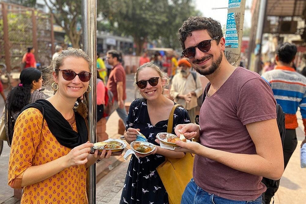 “Three joyful travelers sample spicy street snacks near Gavipiuram Cave Temple in Bangalore, Karnataka, India, capturing vibrant local culture, bustling markets, flavors and culinary experiences.”  “Three joyful travelers sample spicy street snacks near Gavipiuram Cave Temple in Bangalore, Karnataka, India, capturing vibrant local culture, bustling markets, flavors and culinary experiences.”